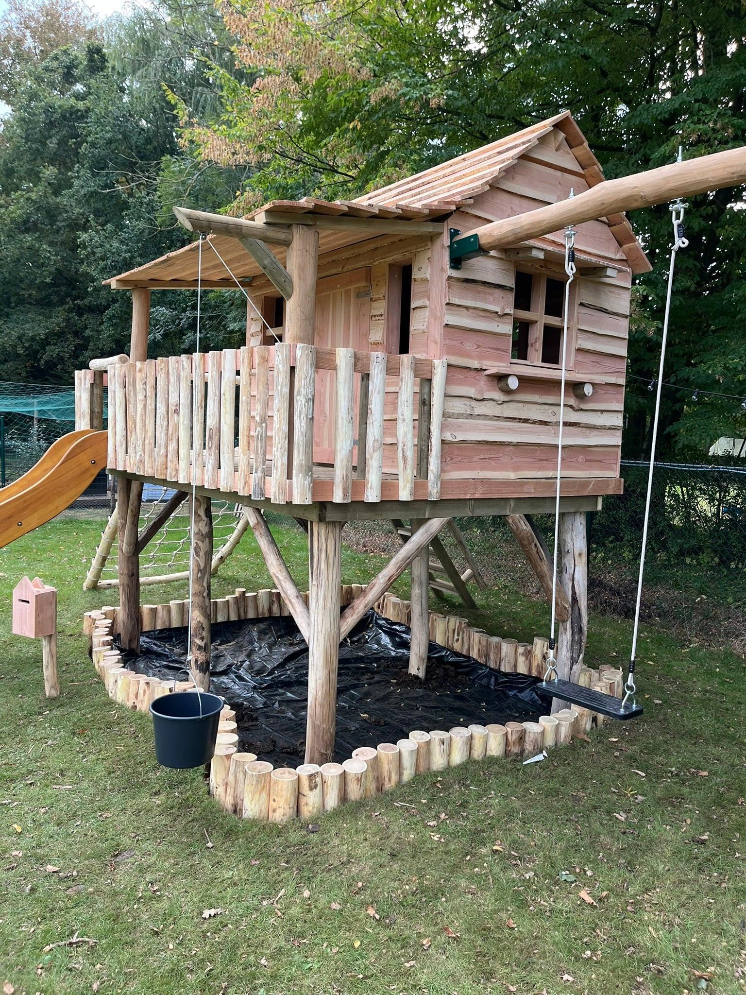 Zandbak met Robinia omrandingZandbakken speelhuisje buiten.