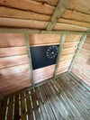 Krijtbord met klok aan de wand van een houten speelhuisje